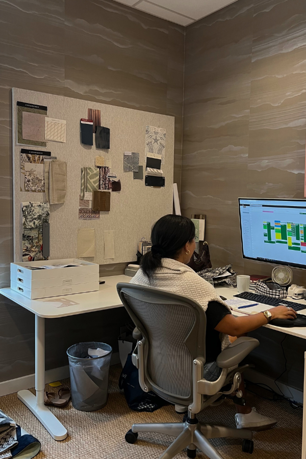 a designer sits at her desk with a mood board next to her while working at her computer
