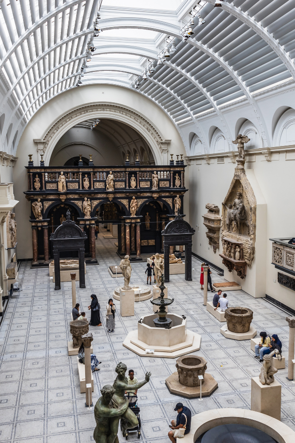 The Victoria and Albert Museum's sculpture gallery in London featuring historic artworks beneath a vaulted glass ceiling.