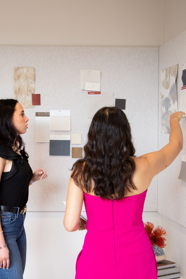two designers in a studio pinning paper to a mood board